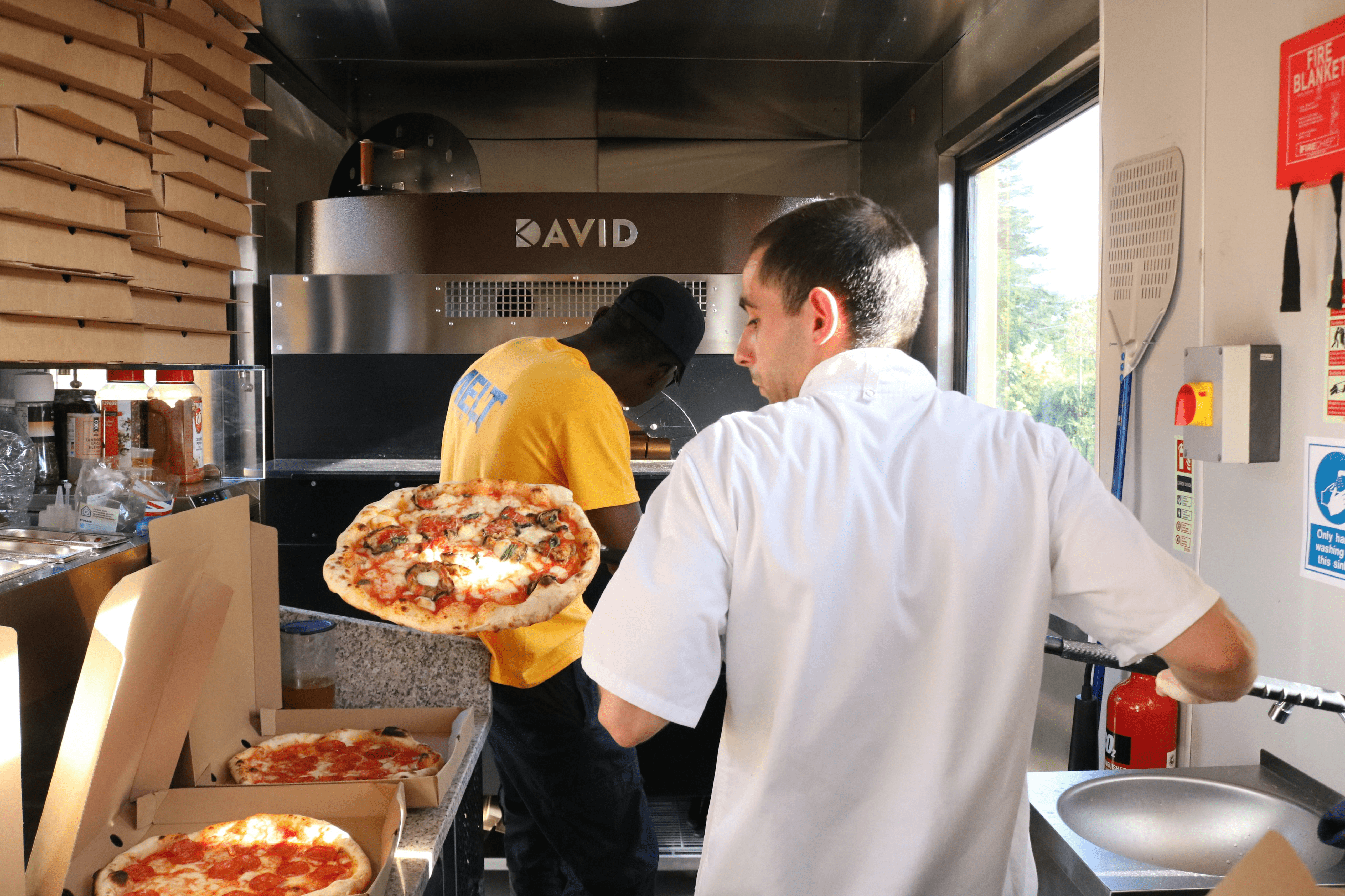 the melt pizza staff is making pizza in a stone oven