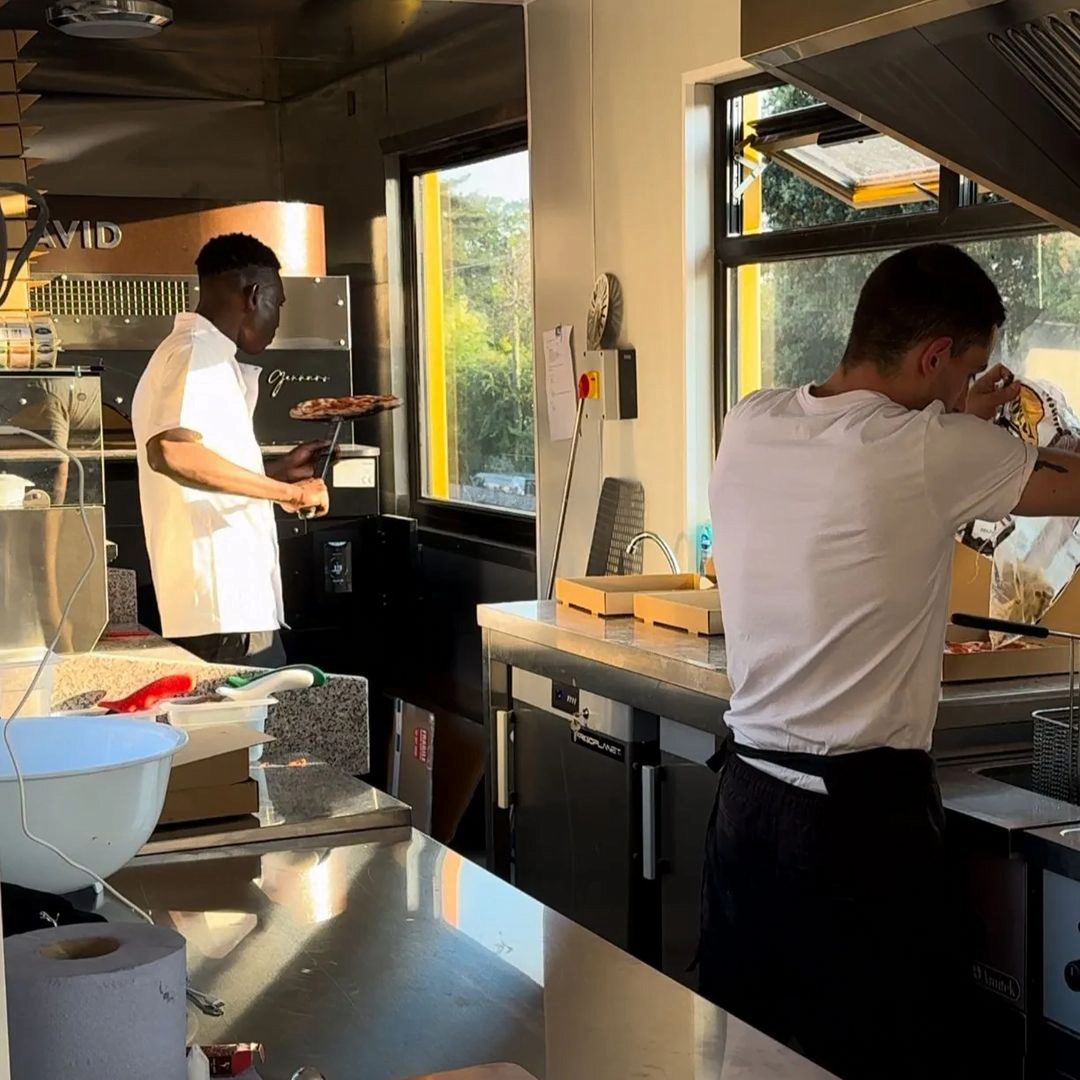 the melt pizza staff is making pizza in a stone oven